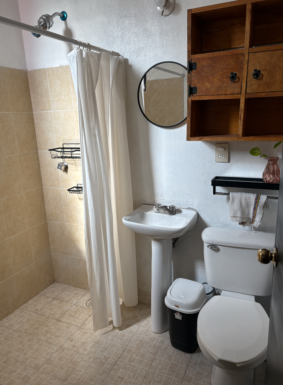 Private bathroom with shower, round mirror, and shelving.